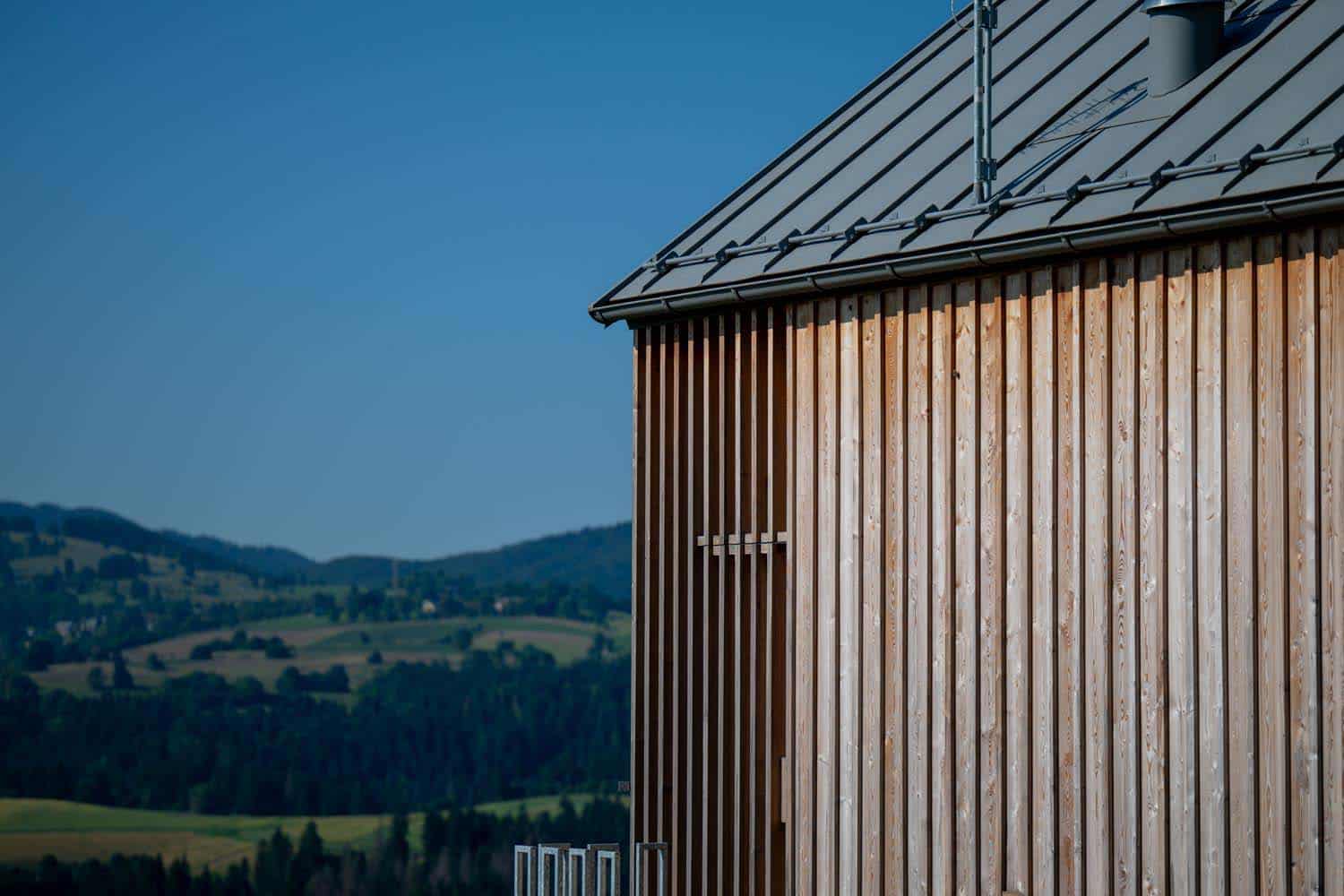 Soggiorno con camino in cemento grezzo e vista panoramica sull'Altopiano di Asiago