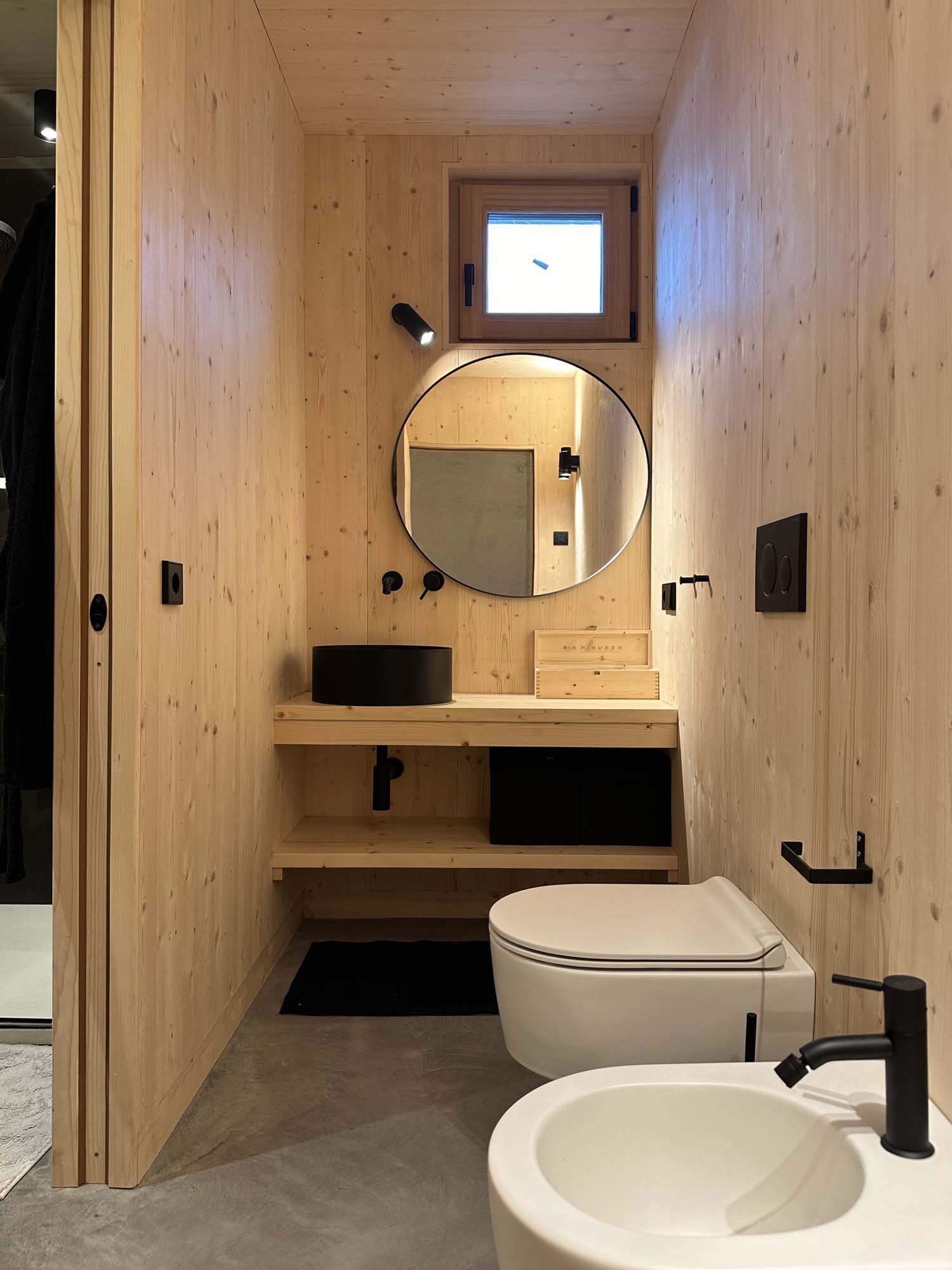 Bagno minimalista con rivestimento in cemento e lavabo sospeso