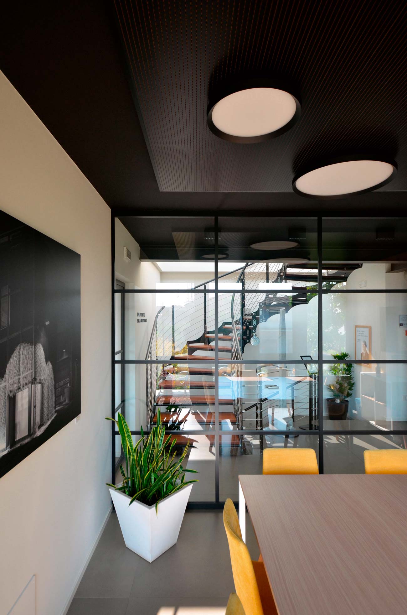 Dettaglio postazione di lavoro con pianta e parete vetrata nera