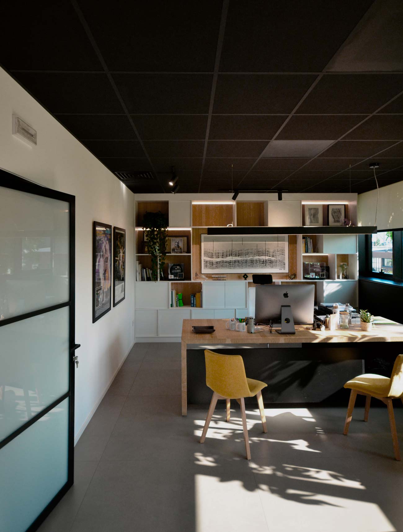 Area bar Sapiselco con bancone giallo, sgabelli neri e parete verde